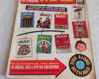 May include: The 6 Worst From MAD Annual, a collection of humor and satire from past issues.  The cover features a red and white MAD logo with a collection of MAD magazine covers hanging from a string.  The magazine cover also includes a special free bonus, a real 33 1/3 RPM record from their new hit/flop album.  The cover also features the text "Fink Along With MAD".