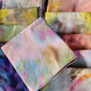 May include: A stack of colourful fabric squares with tie-dye patterns in shades of pink, blue, green, yellow, and purple.