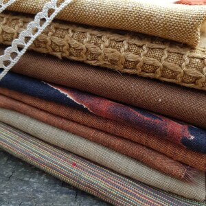 Puede incluir: Un conjunto de ocho muestras de tela en diferentes tonos de marr&oacute;n, beige y &oacute;xido. Las telas tienen diferentes texturas, incluyendo tejido, lino y arpillera.