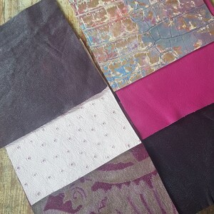 May include: A collection of six different leather swatches in various colors and textures, including a dark purple, white with small dots, a purple and brown patterned leather, a dark purple, a bright pink, and a light blue and brown patterned leather.