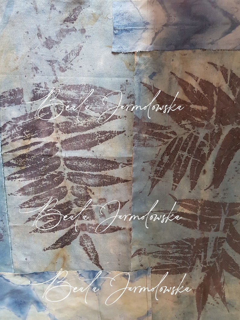 May include: A close-up of a fabric art piece with a blue and brown color scheme. The fabric is textured and has a pattern of leaves. The artist's name, "Beata Jarmolowska", is written in white cursive on the fabric.