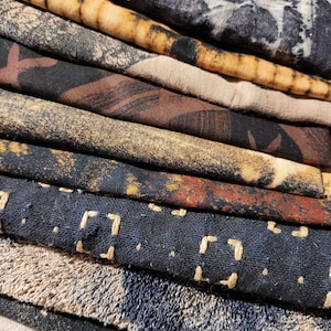 Peut inclure: Une pile de chutes de tissu dans différentes nuances de brun, noir et beige. Les tissus ont des textures différentes, y compris lisses, texturées et tissées.