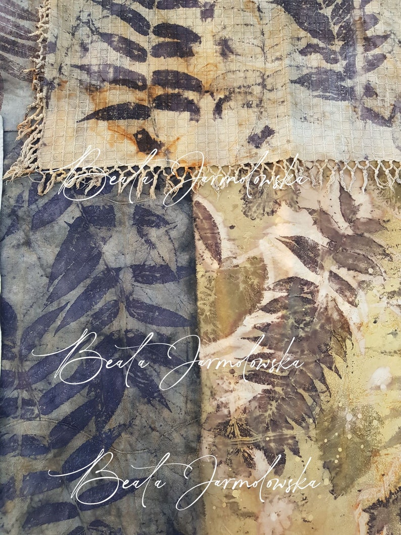 May include: A close-up of two fabric squares with a leaf pattern. The fabric is a light beige color with brown and black leaf patterns. The fabric is textured and has a fringe border. The name "Beata Jarmolowska" is written in white cursive on the fabric.