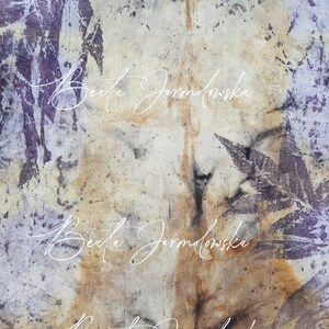 May include: A close-up of a light brown fabric with a purple leaf pattern and the text "Beata Jarmolowska" written three times in white cursive.