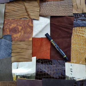 Op de afbeelding: Een selectie van lederen swatches in verschillende kleuren en texturen, waaronder bruin, zwart en wit. Een zwarte markeerstift ligt op de swatches.