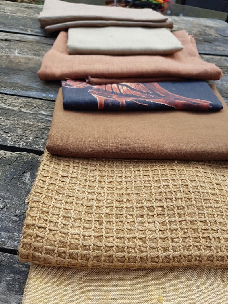 Puede incluir: Una pila de muestras de tela en varios tonos de marr&oacute;n, beige y negro. Las muestras est&aacute;n dispuestas en una pila vertical, con la tela m&aacute;s oscura en la parte inferior y la tela m&aacute;s clara en la parte superior.