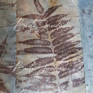 May include: A close-up of a fabric art piece with a brown leaf pattern and the text "Beata Jarmolowska" repeated three times.