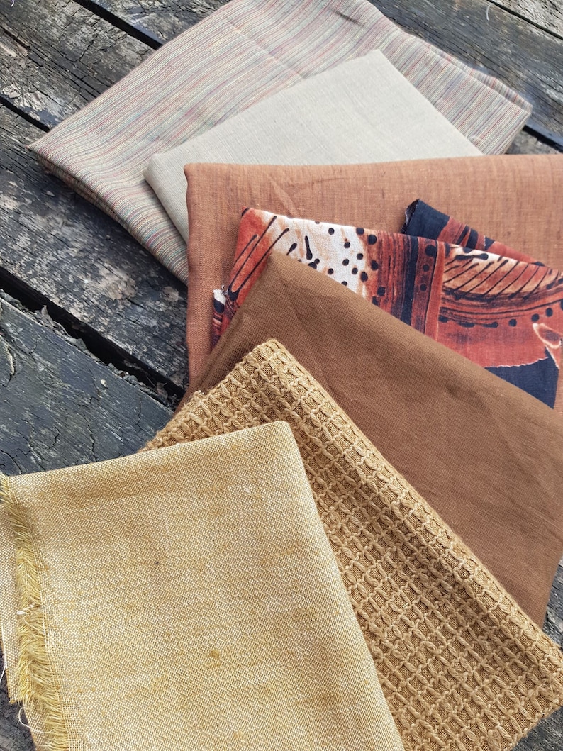 Puede incluir: Un conjunto de seis muestras de tela en varios tonos de marr&oacute;n, beige y tostado. Las telas tienen diferentes texturas, incluyendo un patr&oacute;n tejido, un lino liso y una tela estampada con puntos negros y blancos.