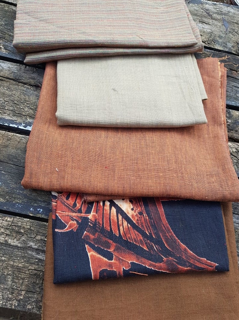 Puede incluir: Un conjunto de cinco muestras de tela en varios colores y patrones. La muestra superior es una tela a rayas en tonos de marr&oacute;n, verde y blanco. La segunda muestra es una tela beige claro. La tercera muestra es una tela de color &oacute;xido. La cuarta muestra es una tela azul oscuro con un patr&oacute;n de color &oacute;xido. La muestra inferior es una tela marr&oacute;n.