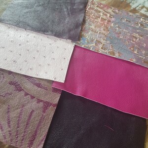 May include: Six different swatches of leather in various colors and textures, including a dark gray, a light pink with a textured pattern, a bright pink, a dark purple with a floral pattern, a dark gray with a textured pattern, and a light gray with a crocodile pattern.