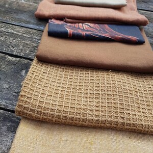 Puede incluir: Un conjunto de ocho muestras de tela diferentes en varios tonos de marr&oacute;n, beige y tostado. Las telas tienen diferentes texturas, incluyendo lisas, tejidas y texturizadas.