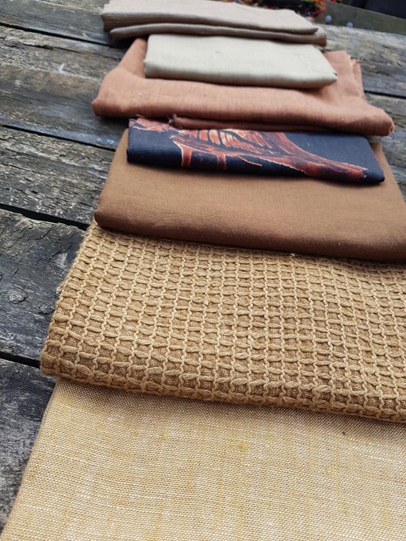Puede incluir: Un conjunto de ocho muestras de tela diferentes en varios tonos de marr&oacute;n, beige y tostado. Las telas tienen diferentes texturas, incluyendo lisas, tejidas y texturizadas.