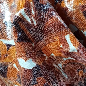 May include: Close-up of a brown and white patterned fabric with a textured surface. The fabric has a subtle sheen and a slightly raised pattern.
