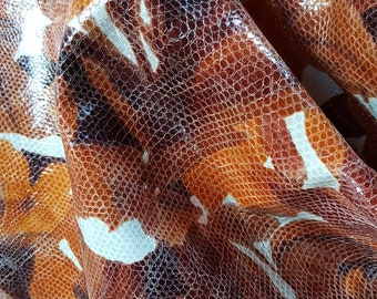 May include: Close-up of a brown and white patterned fabric with a textured surface. The fabric has a subtle sheen and a slightly raised pattern.