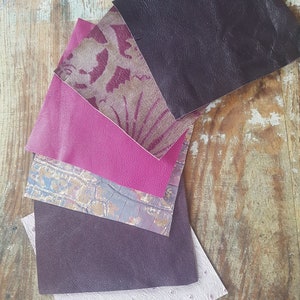 May include: A collection of six different fabric swatches in various shades of purple and pink. The swatches are arranged in a fan shape, with the darkest purple swatch at the top and the lightest pink swatch at the bottom.