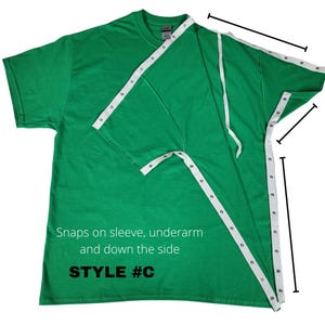 May include: A green t-shirt with white snap tape detailing the sleeve, underarm, and side seams. The text "Snaps on sleeve, underarm and down the side" and "STYLE #C" are printed on the shirt.