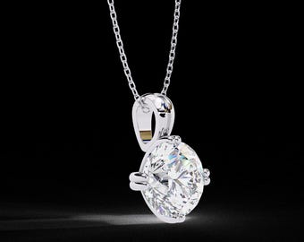 May include: A sparkling diamond pendant necklace. The pendant features a large, round-cut diamond held in a silver setting. The diamond is the focal point, reflecting light and set against a dark background. The chain is delicate and silver.