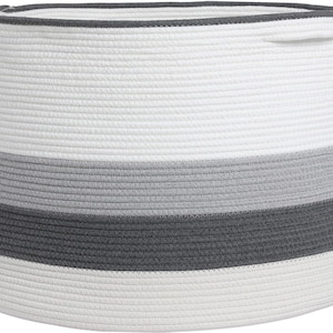 May include: A cylindrical storage basket constructed from coiled rope, featuring horizontal bands of white, light grey, and dark charcoal grey. The basket has a smooth, woven texture and integrated handles on the upper rim for easy carrying.