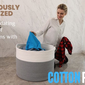 May include: A large, gray and white, round, rope storage basket with a woman putting clothes inside. The basket is labeled "Cottonphant".