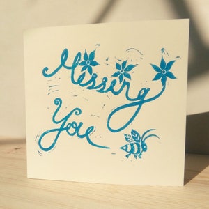 May include: A greeting card with the words "Blessing You" in blue ink. The card features a blue bee and three blue flowers.