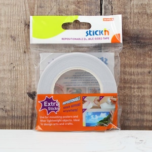 May include: A packet of repositionable double-sided tape. The packaging is clear plastic with orange and yellow details. The text on the packet reads "Extra Sticky" and "Stick almost anywhere!" for mounting posters and lightweight objects.