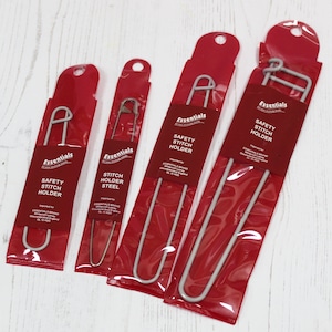 May include: Four different sizes of silver safety stitch holders packaged in red plastic bags. The bags have the text "Essentials" and "Safety Stitch Holder" printed on them.