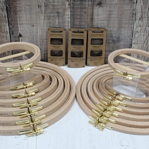 May include: A set of 16 wooden embroidery hoops in various sizes. The hoops are arranged in two groups, with the larger hoops at the bottom and the smaller hoops at the top. The hoops are made of natural wood and have a brass screw closure. The hoops are 8mm and 16mm wide.