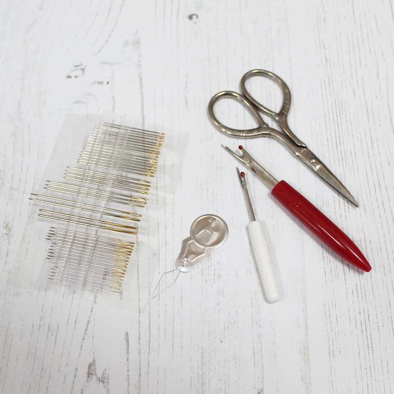 May include: A set of sewing tools including a pack of needles, a needle threader, a seam ripper, and a pair of small scissors.