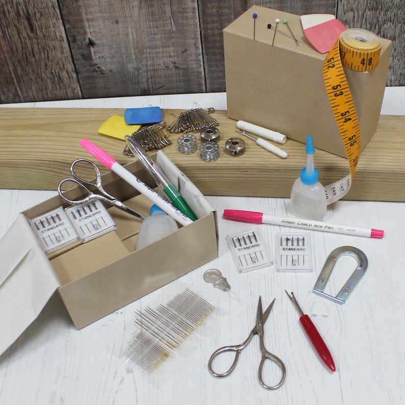 May include: A sewing kit with a variety of tools, including needles, thread, scissors, a thimble, and a tape measure. The kit is organized in a brown cardboard box with a lid.