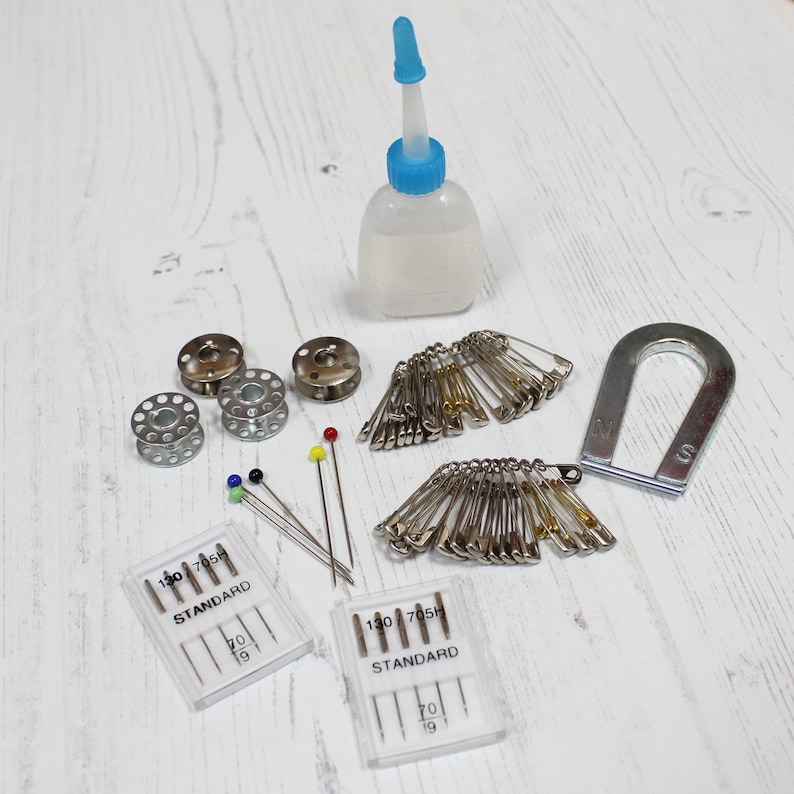 May include: A set of sewing supplies including two packs of needles, two spools of thread, a bottle of sewing machine oil, a magnet, and a pack of safety pins.