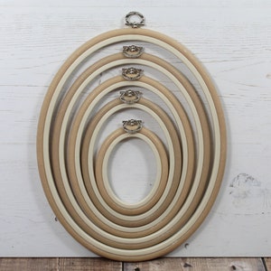 May include: Set of five oval embroidery hoops, nested together, with a natural wood finish and silver metal screw closures.