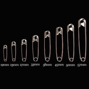May include: A set of ten safety pins in various sizes, ranging from 19mm to 57mm. The pins are arranged in order of size, with the smallest pin on the left and the largest pin on the right.