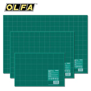 May include: A stack of OLFA brand green cutting mats with grid lines. The mats are in various sizes, with the largest at the back and the smallest in the front. The OLFA logo is in the top left corner.