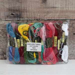 May include: A clear plastic bag filled with 50 spools of embroidery thread in assorted colors. The bag has a label that reads "Embroidery Thread Asst Colors F0816 50PCS/BAG".