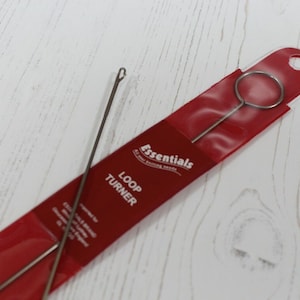May include: Two silver loop turners in a red plastic package. The package says "Essentials All the knitting needs" and "Loop Turner".