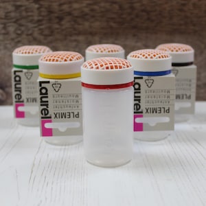 May include: A collection of clear plastic containers with white lids and orange mesh tops. Each container has a colored band around the base of the lid, including red, yellow, green, and blue. The containers have the text "Laurel" and "PLEMIX" printed on them.