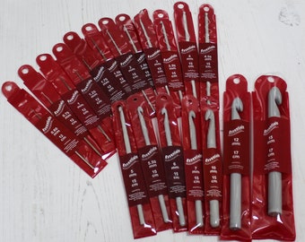 May include: A set of 18 crochet hooks in various sizes, ranging from 0.60 mm to 15 mm. The hooks are packaged individually in red plastic sleeves with the size and measurement in millimeters and centimeters printed on each sleeve. The hooks are made of white plastic.