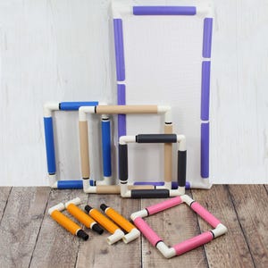 May include: A selection of embroidery hoops and accessories in various sizes and colours. The hoops have white plastic frames with coloured grips in blue, tan, black, pink, and purple. Several orange and black accessories are also included.