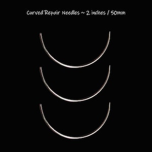 Könnte beinhalten: Drei gebogene Reparatur-Nadeln, jeweils etwa 5 cm lang, werden vor einem schwarzen Hintergrund gezeigt. Die Nadeln sind silberfarben und haben ein glattes, poliertes Aussehen. Der Text "Curved Repair Needles ~ 2 inches / 50mm" befindet sich oben.