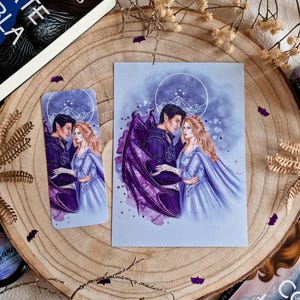 May include: A purple and blue watercolor print of a couple with a purple dragon wing. The couple is standing in front of a white geometric moon with a mountain range inside. The print is on a white background.