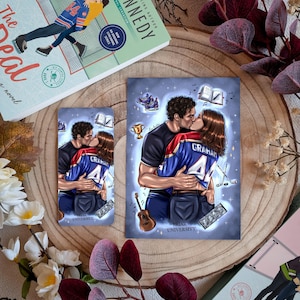 Könnte beinhalten: Ein Buch und zwei Kunstdrucke mit einem sich umarmenden Paar, mit dem Text "GRAHAM" auf einem Trikot. Das Buchcover zeigt ein Paar auf Schlittschuhen. Die Drucke und das Buch liegen auf einer Holzoberfläche mit floralen Akzenten.