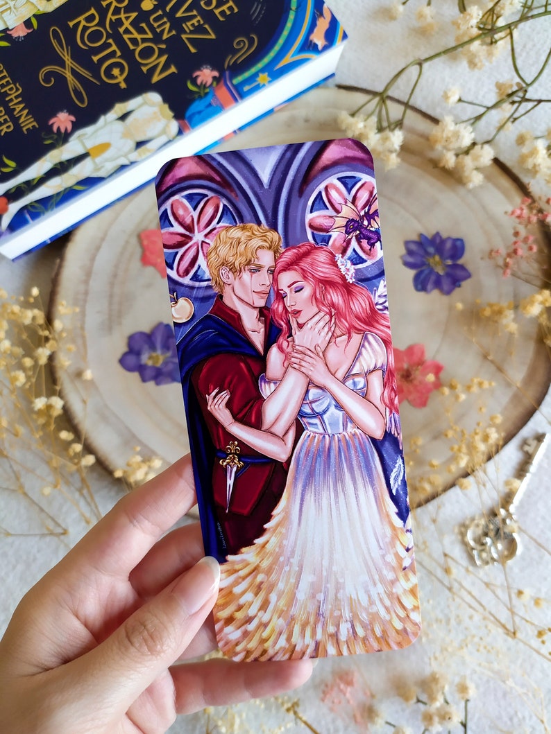 May include: A bookmark featuring a romantic illustration of a couple in a gothic setting. The man is wearing a red and blue outfit, while the woman is wearing a white dress with a pink bodice. The background is a stained glass window with a floral design.