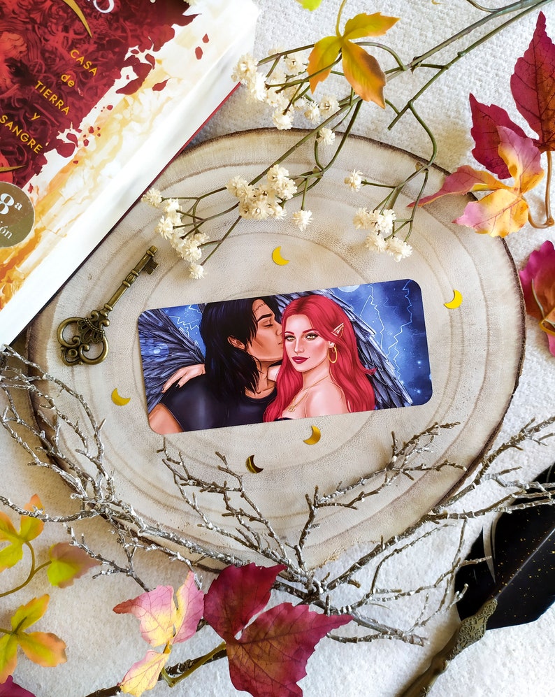 Puede incluir: Una tarjeta con una pareja en ella. El hombre tiene el pelo oscuro y lleva una camisa negra. La mujer tiene el pelo largo y rojo y lleva un vestido negro. El fondo es azul oscuro con rayos.