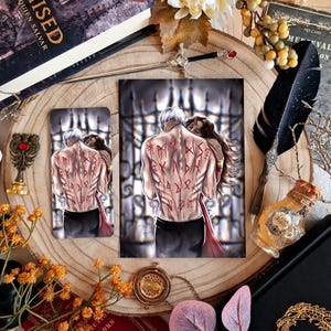 May include: An artistic print and phone case featuring a couple embracing, with red runes on the man's back. The image is surrounded by decorative elements like a feather, a sword, and a book with the title "CHEMISED".