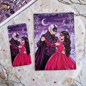Può includere: Una coppia in costume da maschera danza in una foresta innevata sotto una luna crescente. L'uomo indossa un abito nero con un mantello viola e una maschera nera. La donna indossa un vestito rosa con una maschera rossa. Lo sfondo è un cielo viola con stelle bianche.