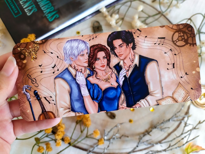 May include: A bookmark featuring a romantic illustration of three people, two men and one woman, with musical notes and a vintage aesthetic. The woman is wearing a blue dress and the men are wearing blue and white shirts. The bookmark has a gold background with a gold gear design.