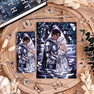 May include: A rectangular art print and a matching bookmark featuring a digital illustration of a knight in silver armour embracing a figure in a white dress while standing in water. The scene includes glowing butterflies, a stone gargoyle, and a sword.