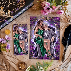 Puede incluir: Ilustración de una pareja con vestimenta formal, la mujer con un vestido verde, el hombre con un traje gris. La obra de arte está en un marcapáginas y una impresión más grande, rodeada de acentos florales morados. También hay un libro y accesorios dorados.