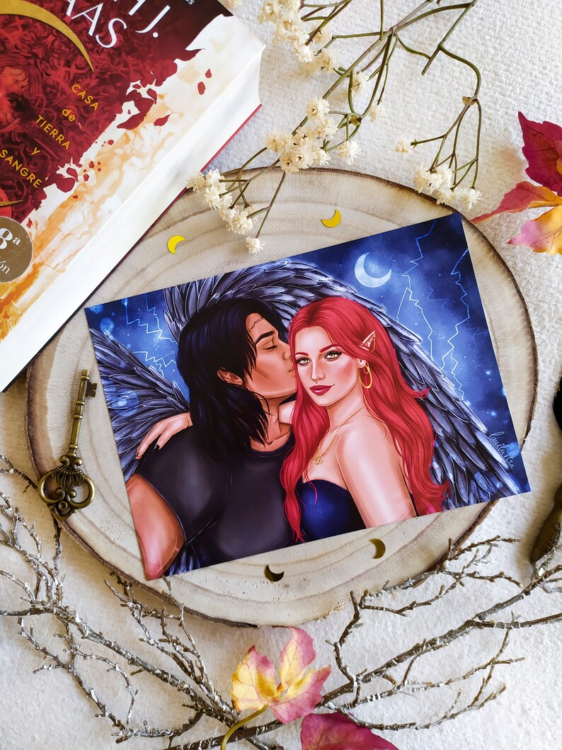 Puede incluir: Una impresi&oacute;n de una pareja abraz&aacute;ndose, la mujer tiene el pelo rojo y lleva un vestido negro, el hombre tiene el pelo negro y lleva una camisa negra, est&aacute;n frente a un fondo azul oscuro con estrellas y una luna creciente.