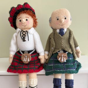 Può includere: Due bambole fatte a mano all'uncinetto vestite con abiti scozzesi tradizionali. Una bambola indossa un kilt a quadri rossi e verdi, una camicia bianca e un cappello rosso. L'altra bambola indossa un kilt a quadri verdi e blu, una giacca verde e una cravatta blu.